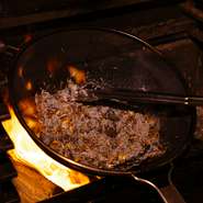 蟹の身とモリーユ茸を大きなザルに入れ、燃え盛る炎に翳して炙り焼く様もダイナミックかつ臨場感たっぷり。こうして焼くことで「具全体に満遍なく香りがつく」とは田代さん。宮崎の炭火焼鳥がヒントになったそうだ。