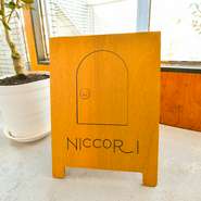【NICCORI】のロゴマークに描かれた扉のイラスト。ドアノブのスマイルマークには「心のドアを開けて笑顔になっていただきたい」との思いが込められています。