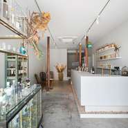 白を基調としたギャラリーを彷彿させる空間で、飲む人も飲まない人も共に愉しめるお店。壁際に並んだボトルはひとつ一つがアートにもなっていて、ラベルを眺めることも愉しみの一つです。