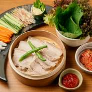 サンチュとえごまで、蒸し豚・野菜・キムチ・特製味噌を包んで食べる、韓国の伝統料理です。柔らかく茹でた豚肉は、甘さと旨みが凝縮された、しっとりとした食感。自家製の辛味噌の融合がクセになる味わいです。