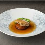 約80グラムの大きめの鮑を使用した一皿です。鮑を親鳥や生ハムと共にオイスターソースで煮込み、大根を挟んで仕上げているのが特長。豊かな風味と滑らかな食感が楽しめます。