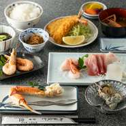 定番の人気メニュー。ズワイガニ 1本・刺身・サザエのつぼ焼き・フライなど、店の定番料理を詰め込んだ、欲張りな定食です。なお、季節や仕入れにより内容は変更となります。