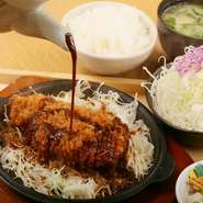 熱々の鉄板にのせられた揚げたてのとんかつに、赤みそだれをかけていただく『名物　鉄板みそかつ定食』。名古屋で愛される本場の味を、【とんかつ玉藤】流にアレンジしてあります。くせになるおいしさをぜひ！