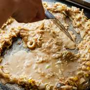 もんじゃには【もんじゃ麦】創業時から変わらない秘伝の自家製出汁が使用されており、鉄板でジューと焼き上げたおこげの旨味は抜群！じゅわ～っと口の中に広がる美味しさはクセになること間違いなしです。