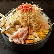 月島本店で愛され続けている看板のもんじゃ焼きです。豚バラ・エビ・イカ・しめじ・エノキ・コーン・ちくわ・ツナ・きりいか・桜えびの10種の素材が織り成すハーモニーを是非お楽しみください。