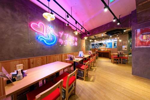 ピンクのネオンが映えるかわいい店内。1階と地下で132席をご用意