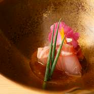 料理を盛り付ける器には日本各地の焼き物が用いられ、その多彩な表情が美しい。吉野桧のカウンター席は、和の趣を生かしたシンプルかつ洗練されたデザインで、木の温もりが心地良さを醸し出しています。