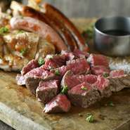 肉を食べる喜びにひたれるドラマチックな皿。黒毛和牛ステーキ、北海道夢の大地豚肩ロースステーキ、若鶏のグリル、ソーセージ4種グリルを豪快に盛り合わせ。食べ比べると、あらためて和牛の味わいに感服！
