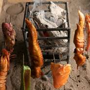 ドアを開ければ、入り口のすぐそばに囲炉裏があり、ほのかに漂う備長炭の香りがほっこりとした気分にさせてくれます。食材が焼ける様子や音、ニオイなど五感で楽しめるのが醍醐味です。