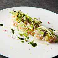 魚の種類は日替わりで、この日はサクラマス。分厚く切った身を表面だけミキュイに焼き上げ、スモークサーモンのイメージで。この日は旬のウルイとウドのピクルス、ディルやバジルのオイルと合わせて提供しています。