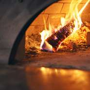 パチパチと薪が燃える音、焼き上がりとともに広がる香り……料理が完成するまでのプロセスも楽しめる薪窯は、オープンキッチンの中央に構えているため、どの席からも一望できます。