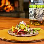 生地は現地で食べられるものと同じく、トウモロコシの粉のみで練り上げます。具材はスパイスやフルーツでつくるソースを塗って焼いた肉。出来たてを豪快に挟み、サルサで爽やかに仕上げています。