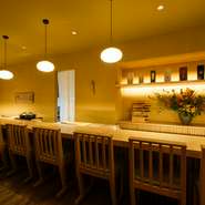 約9mもの天然木の一枚板カウンター席がメイン空間。オープンキッチンの設えとし、冬季はカニ、夏季はうなぎや鱧などをゲストの目の前でさばき、調理のライブ感を届けています。五感が喜ぶ食体験をぜひ、ここで。