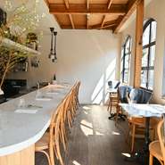 オープンキッチンを中心にした店内は、清潔感のある白を基調にあたたかな木目を取り入れたリラックスした雰囲気。パートナーと並んでカウンターに腰を下ろせば、シェフの調理風景を間近に見られます。