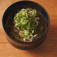 飲んだ後の軽い〆にピッタリのお椀サイズの汁そば。スープは、鶏がらと豚の背骨をべースに、ネギや生姜、セロリ、人参を加え、3～4時間じっくりと煮込んでいる。具は、たっぷりのネギとみょうがのみというのも潔い。