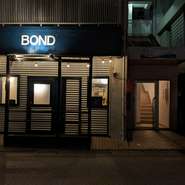 2023年4月、那覇市壺川にオープンした【炭火焼き鳥BOND（ボンド）】。従来の焼き鳥店のイメージを覆す、スタイリッシュな外観が目を惹きます。イタリアンをベースとした一品料理も揃い、ワインとともに楽しめます。