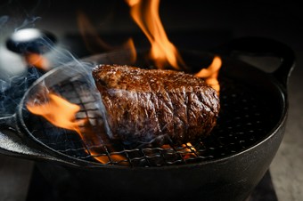 豪快に立ちのぼる炎の中、高温の藁で表面を焼き上げる『特選和牛のステーキ』