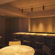 自然な色合いと手仕事にこだわった店内。カウンターは砂の質感のある素材、チェアは高さ1mのミドルチェアにすることで、長時間くつろいで座れるように。壁は伝統的な職人技「かき落とし」の技法を使用。