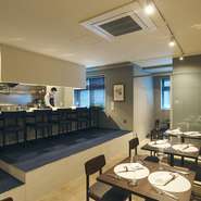 厨房に面するカウンター席なら、シェフと話がしやすく、臨場感たっぷりに調理を眺められます。内装を担ったデザイナーが青く塗った椅子もオシャレで、座り心地も抜群。そこでワインを飲めば、一人でも優雅な気分に。