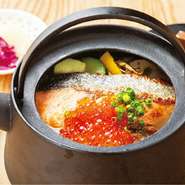 鉄瓶でアツアツに仕上げるのがモスケスタイル。塩麹と野菜を、鯛や鰹など複数のだしを煮込み、優しい味に仕立てただし汁に、香ばしく焼き上げた鮭とたっぷりのいくらを乗せたちょっと贅沢な雑炊です。