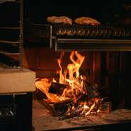 カウンター越しに眺める、焼き台の臨場感も見応え抜群です。薪焼きグリルと炭焼き、それぞれで用意された専用スペースも、お肉のおいしさに向き合い続ける【火乃香】ならではのこだわりです。