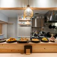 カウンター席から、料理人の繊細な手仕事を眺めることができます。アットホームな雰囲気の中で、自由におばんざいを選べる幸せの時間。あちらこちらから、うれしそうな笑い声が聞こえてきます。