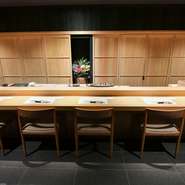 抑えめのライティングが落ち着いた雰囲気を演出し、長い一枚板のカウンターが木の温もりと品格を感じさせます。細部までこだわり抜かれた和の設えにより心地よい空間です。