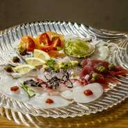 その日仕入れた鮮魚から、4～5種類を盛り合わせています。わさび醤油だけでなく、カルパッチョソースも添えて提供。2つの料理を一度に食べているような、お得な気分に浸れます。