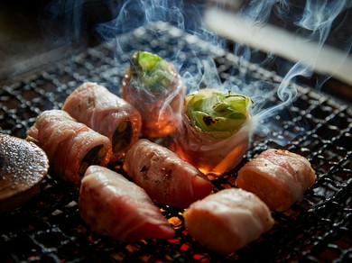 炭火で炙る「名物・県産豚の肉巻き野菜」