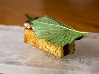 スペインの定番料理を日本の伝統食材で再構築した楽しい一品。牛テールのシェリー酒煮込みの上に、炭火焼きしたうなぎを乗せ、自家製ブリオッシュでサンド。和のハーブ・大葉が海の幸と山の幸をつなぐアクセントに。