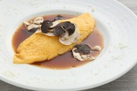 ふわふわのオムレツにトリュフとチーズを削って黒胡椒とブラウンソースをたっぷりかけるシェフ自慢の人気料理のひとつです。