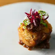 じっくり時間をかけ低温調理を施した『ラム肉のコンフィ』。しっとりジューシーなコンフィをじゃが芋で包みカリカリに焼き上げました。ハーブやアマランスなど愛らしい花と、赤ワインとオニオンのソースを添えて。