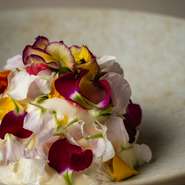 洗練された設計が、料理の彩りを美しく浮かび上がらせます。静謐な設えと鮮やかな皿のコントラストが印象的。上質で穏やかな時の流れがゲストを包み込む、落ち着きのある空間です。